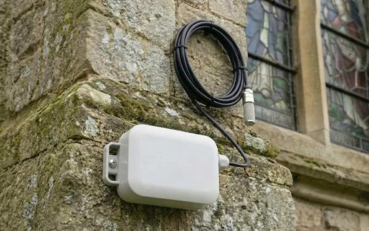 RoomAlyzer Air Outdoor sensor mounted on an exterior stone wall with cable probe, outdoor reference for indoor climate baselines